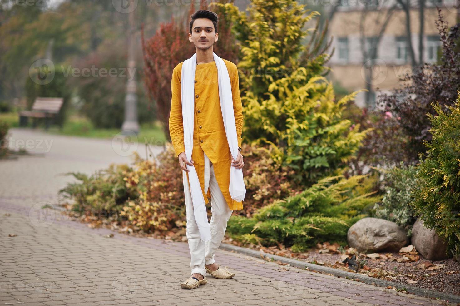 Indian stylish man in yellow traditional clothes with white scarf posed outdoor. photo