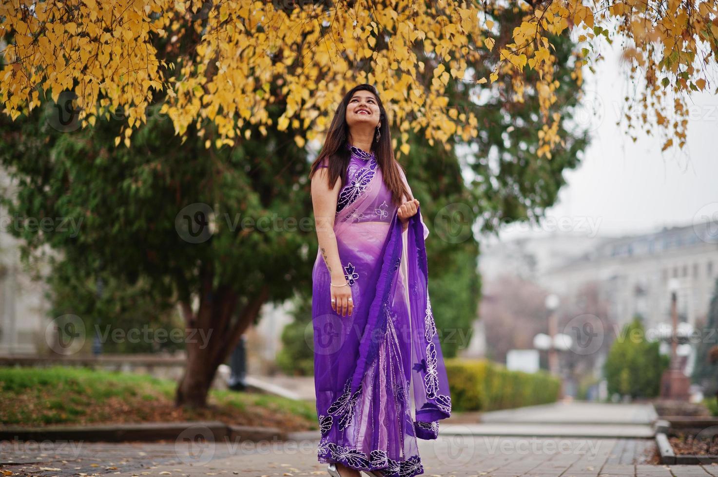 Indian hindu girl at traditional violet saree posed at autumn street. photo