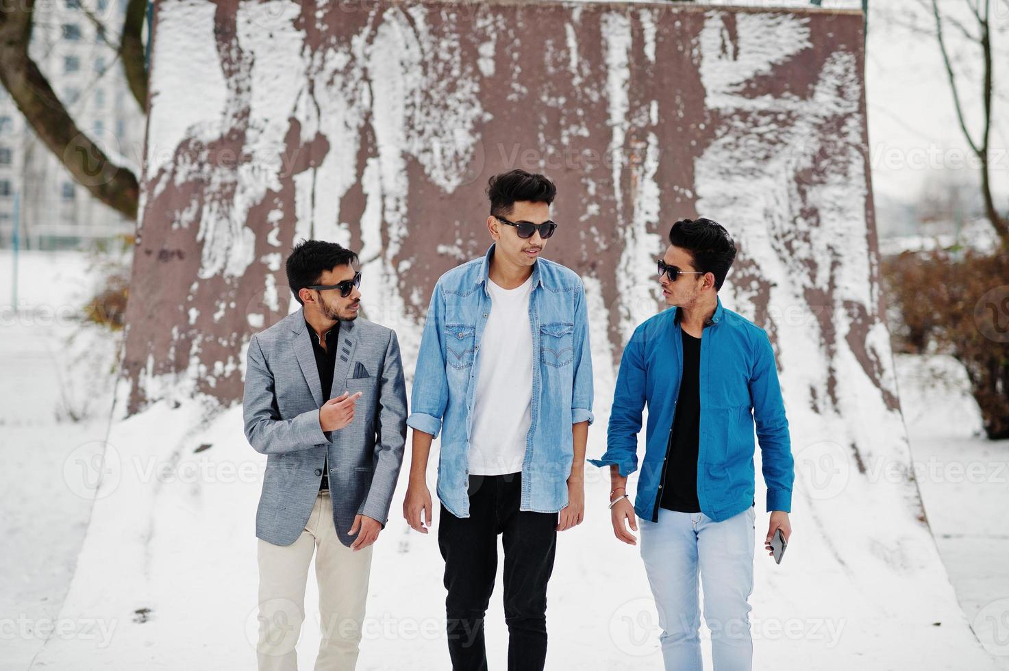 grupo de tres jóvenes indios casuales con gafas de sol posados en el día de invierno. foto