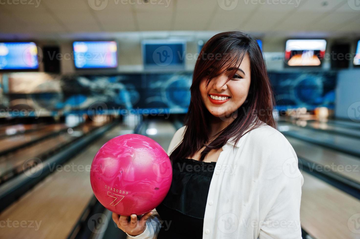 elegante mujer asiática de pie en la bolera con la pelota en la mano. foto