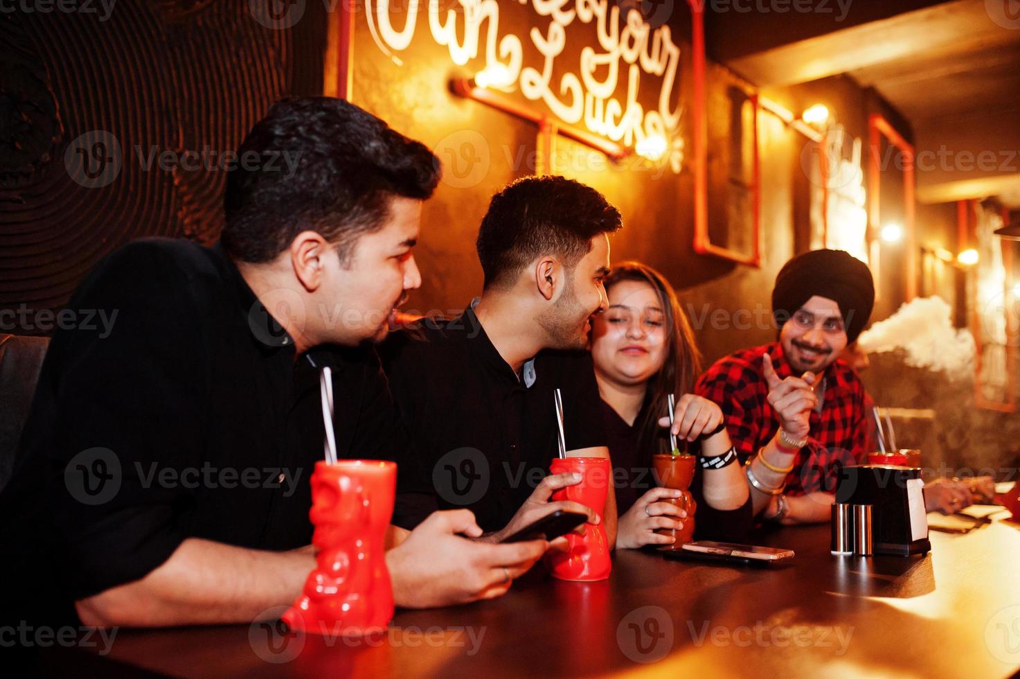 Group of indian friends having fun and rest at night club, drinking cocktails and smoke hookah. photo