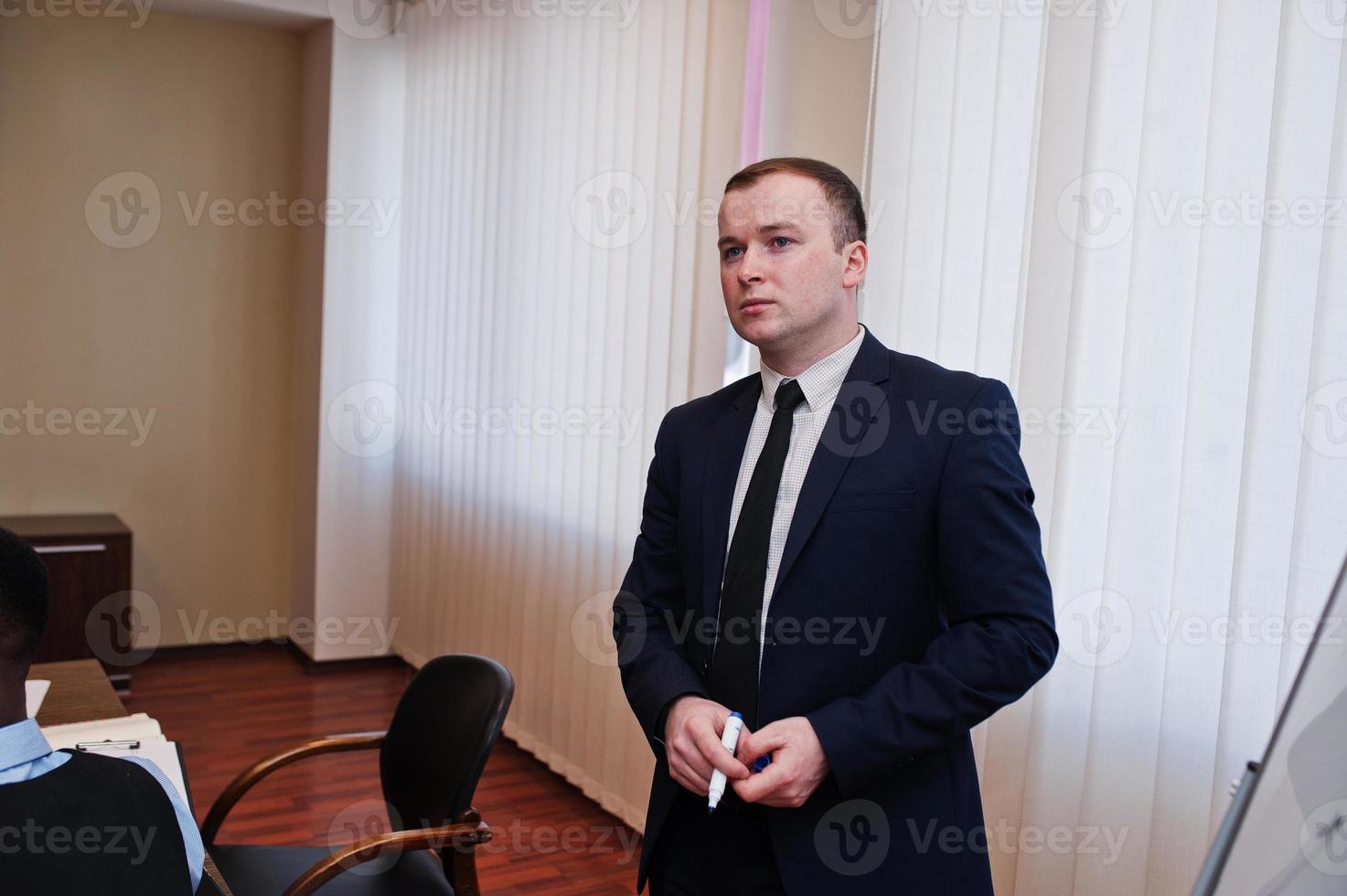 Young creative man at suit in modern office. Successful businessman in coworking. photo