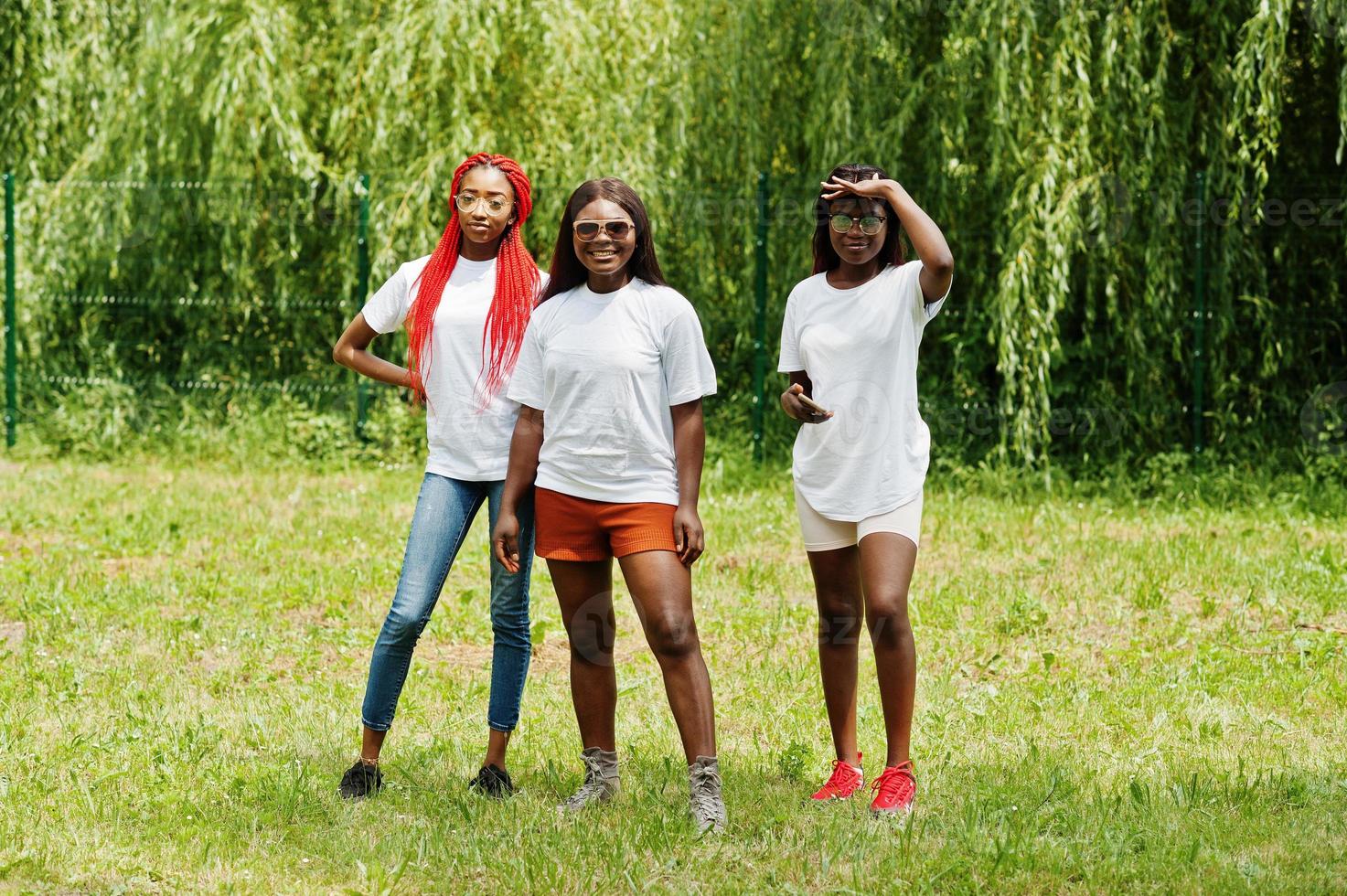 Three african american womans in park at white t-shirts. photo