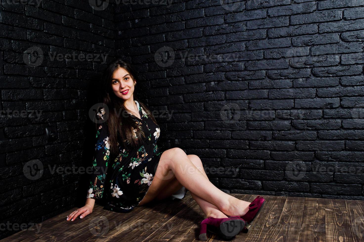 retrato de una joven fabulosa vestida de flores sentada en el oscuro estudio. foto