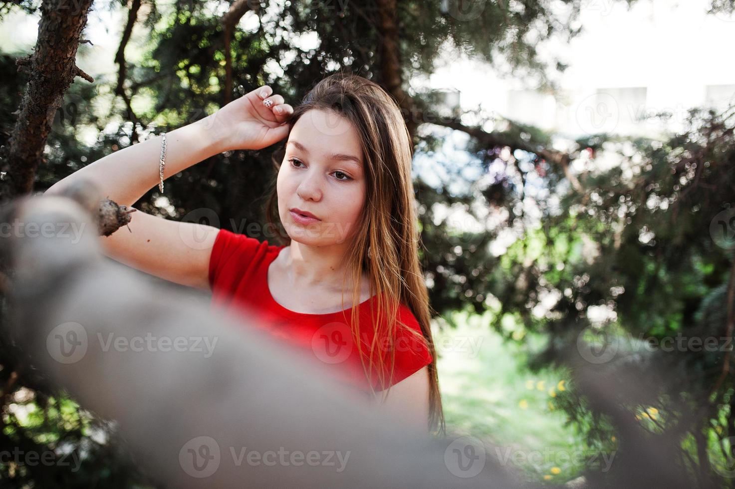 Teenage girl in red dress posed outdoor at sunny day. photo