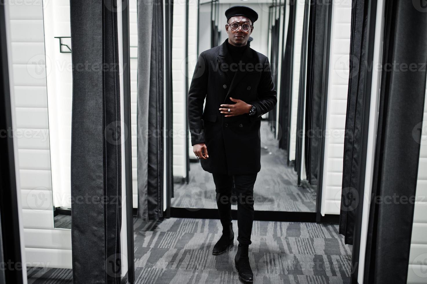 Stylish casual african american man at black beret and overcoat at fitting room clothes store. photo