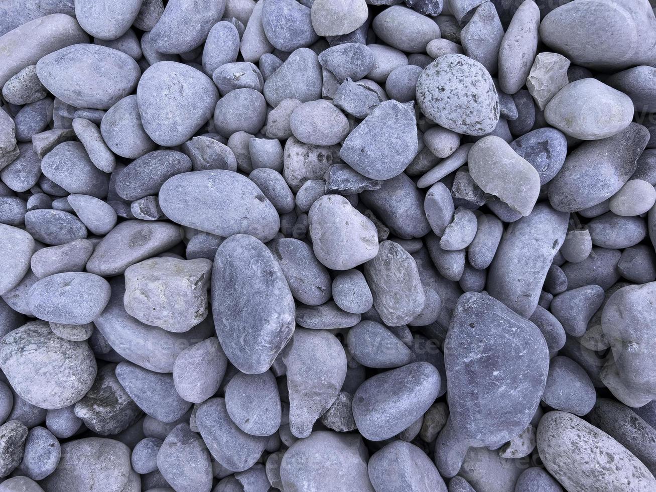 piedras grises redondas en la playa, patrón y textura de guijarros, meditación zen, fondo natural. foto