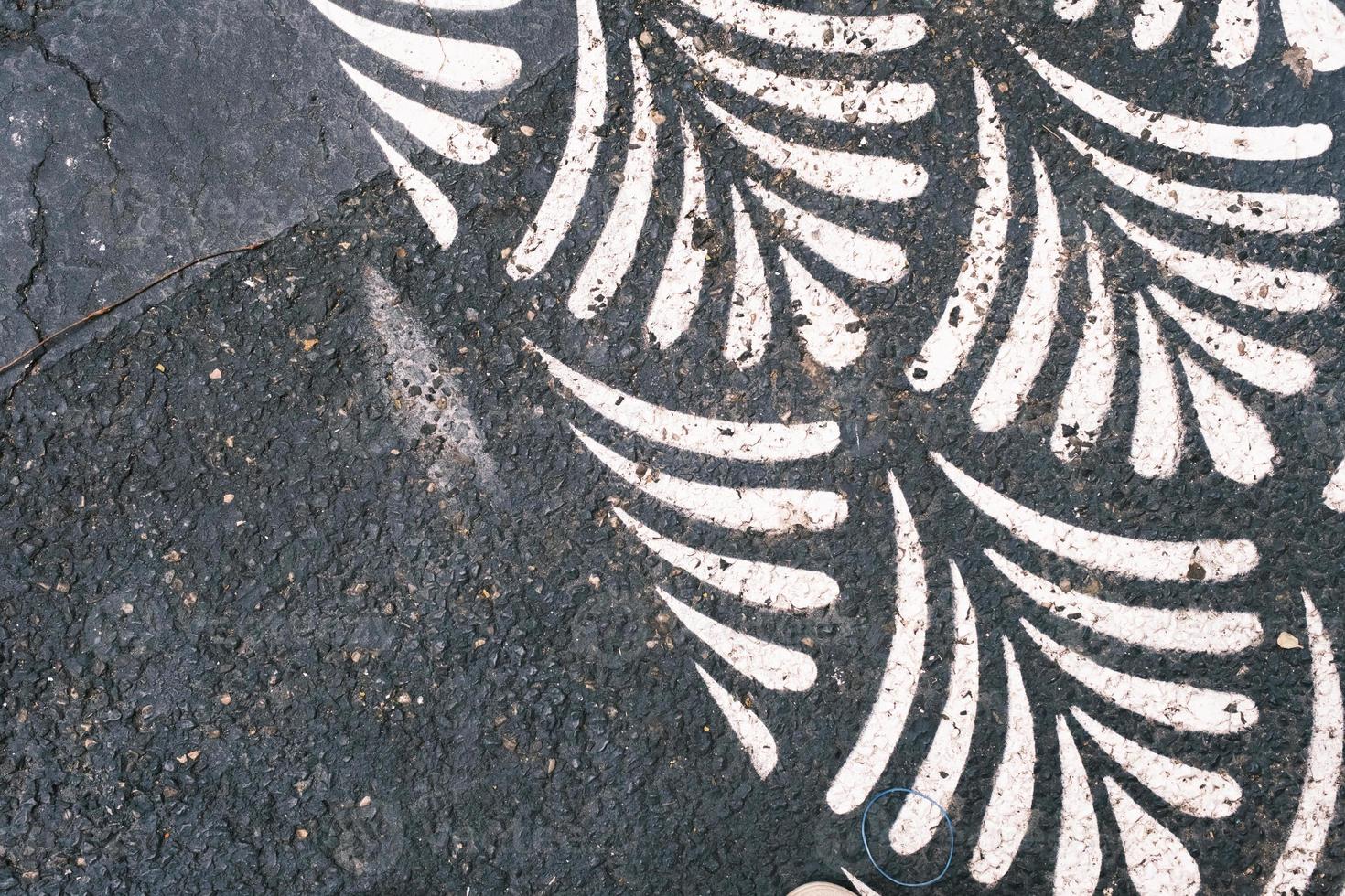 White leaf print on the weathered black asphalt, pattern and texture, weathered textured surface. photo