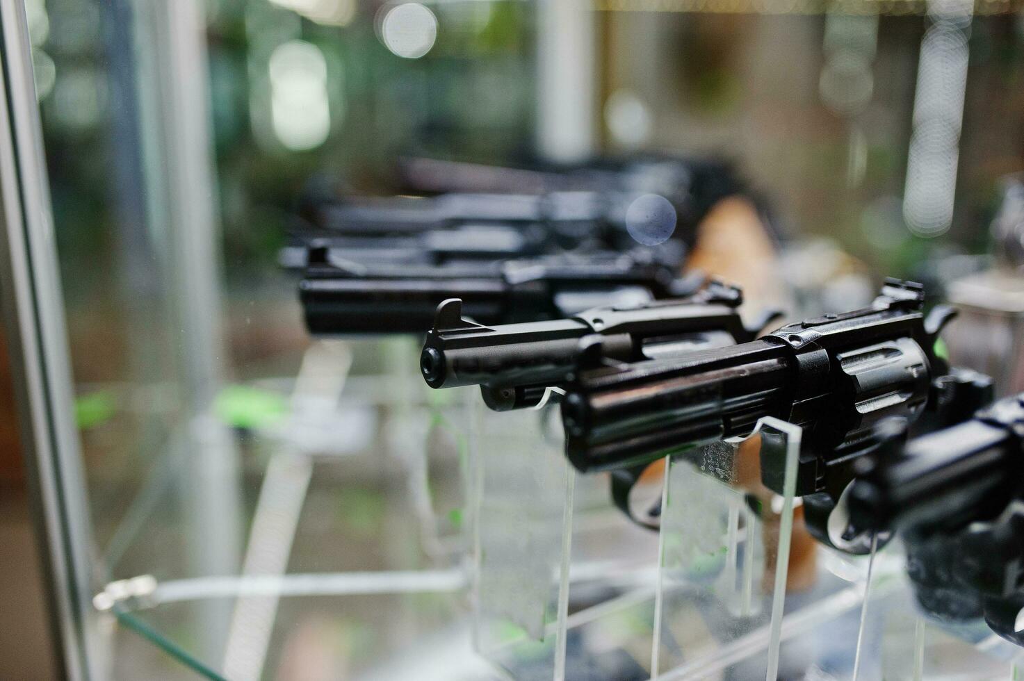 Different guns and revolvers on shelves store weapons on shop center. photo