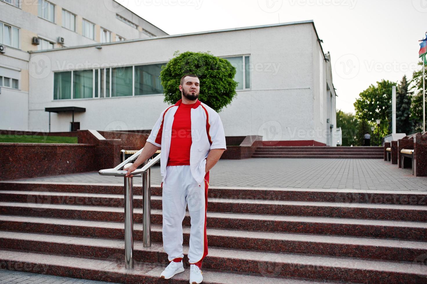 Young brutal bearded muscular man wear on white sport suit with red shirt. photo