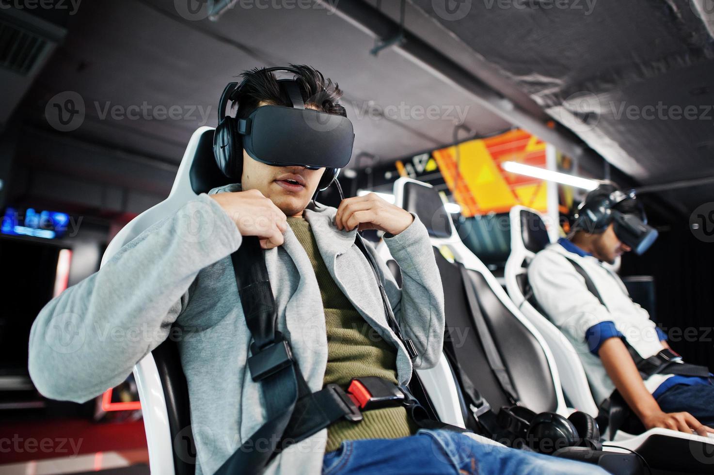 Two young indian people having fun with a new technology of a vr headset at virtual reality simulator. photo