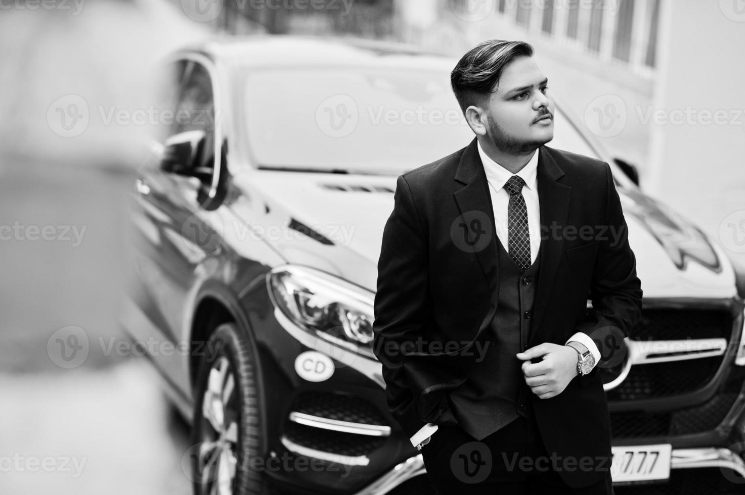 Rich indian businessman in formal wear standing against business suv car. photo