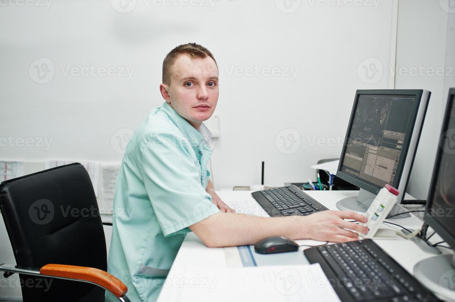 Medical theme. Doctor in the mri office at diagnostic center in hospital, sitting near monitors of computer. photo