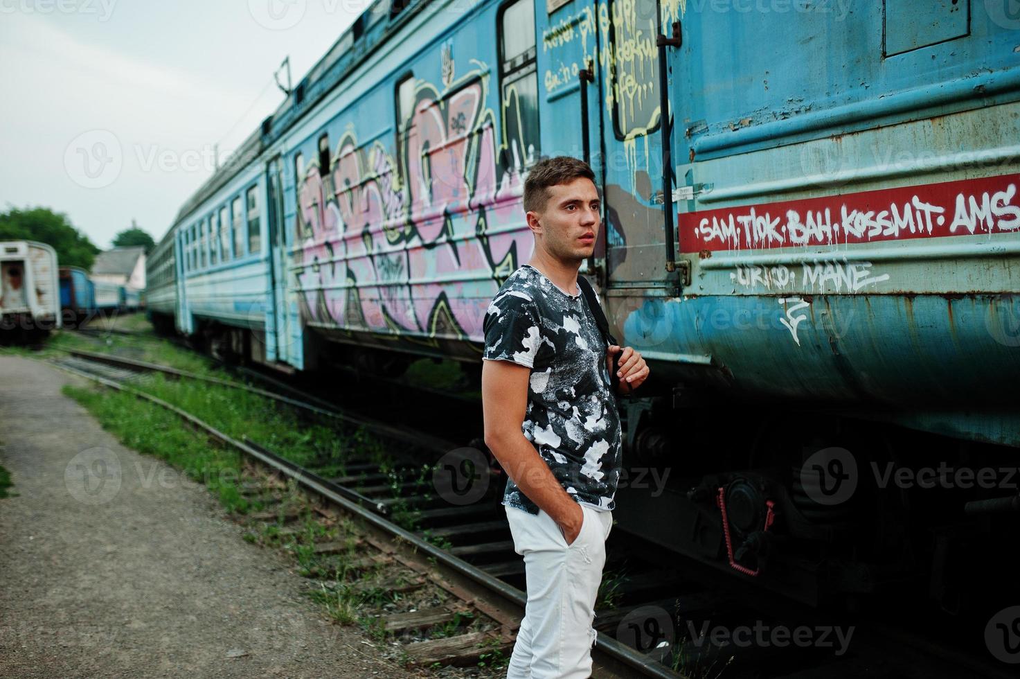 Lifestyle portrait of handsome man with backpack posing on train station. photo