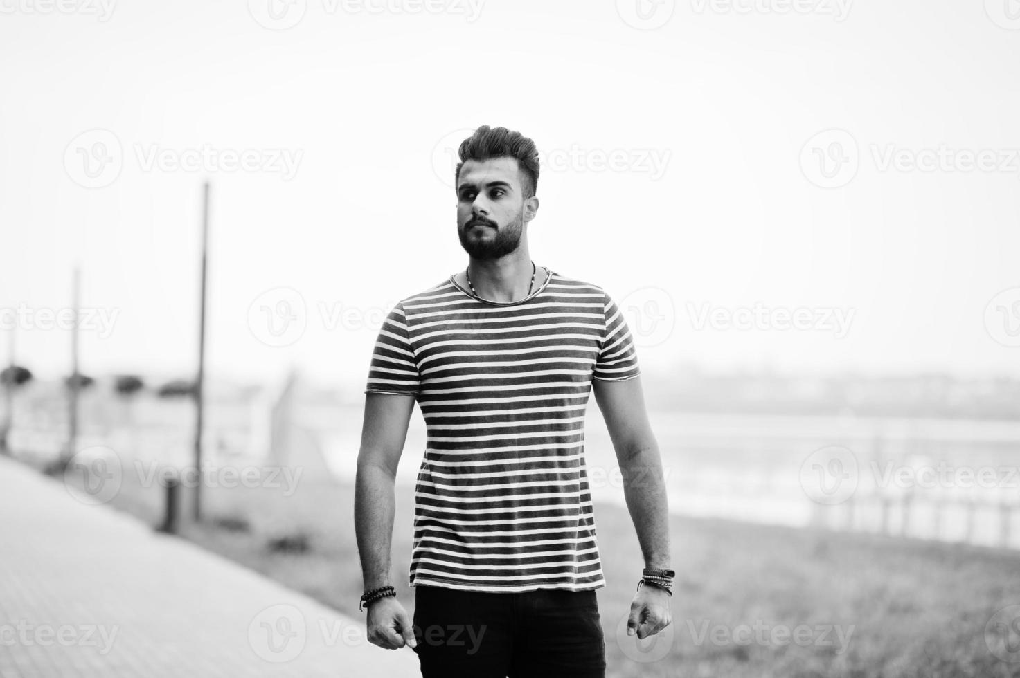 Handsome tall arabian beard man model at stripped shirt posed outdoor. Fashionable arab guy. photo