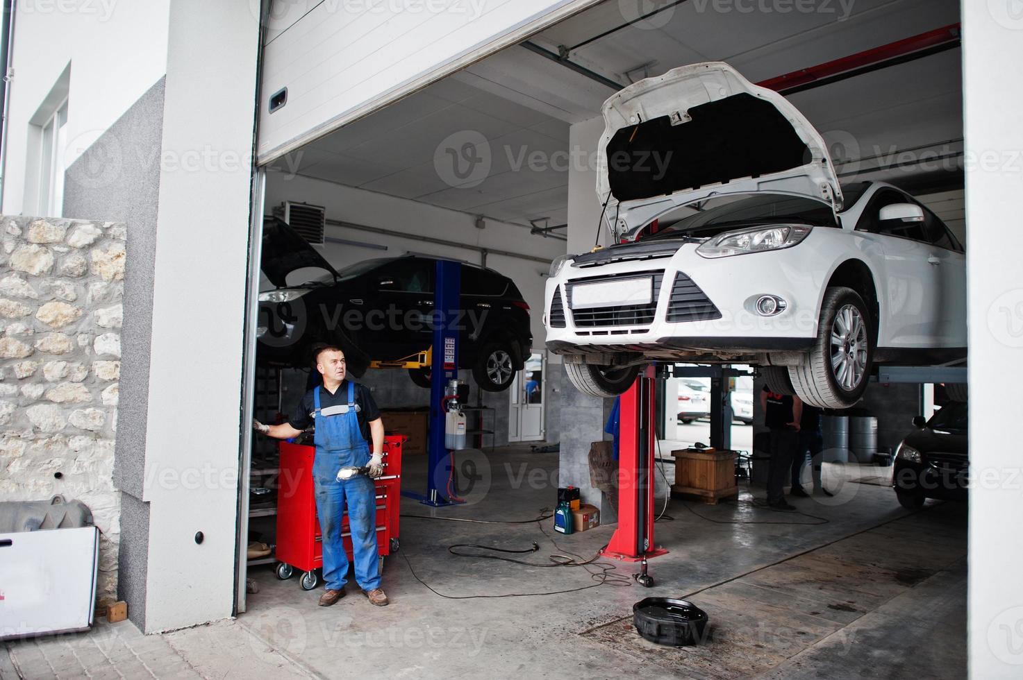 tema de reparación y mantenimiento de automóviles. mecánico en uniforme que trabaja en el servicio de automóviles. foto