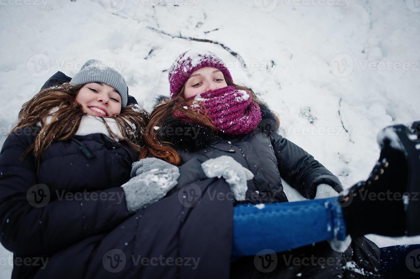 Two funny girls friends having fun at winter snowy day near snow covered trees. photo