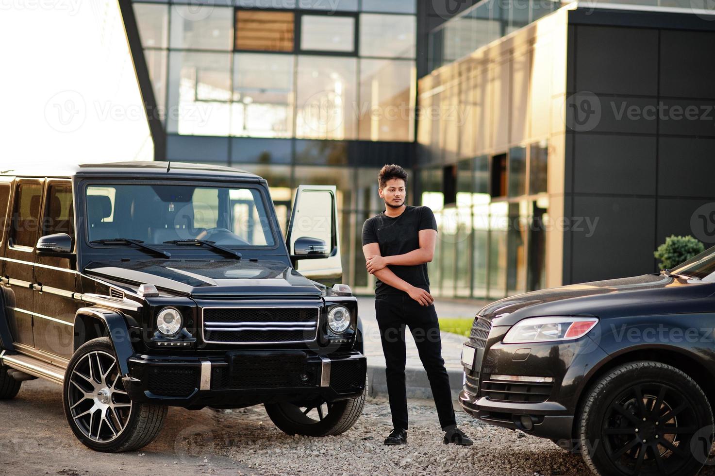Asian man wear on all black posed near suv car. photo