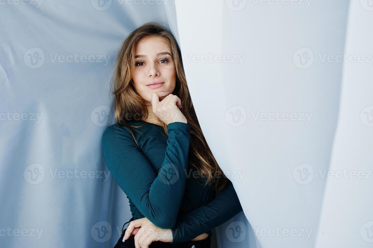 hermosa chica morena vestida de verde, posando en las cortinas. retrato de modelo de estudio. foto