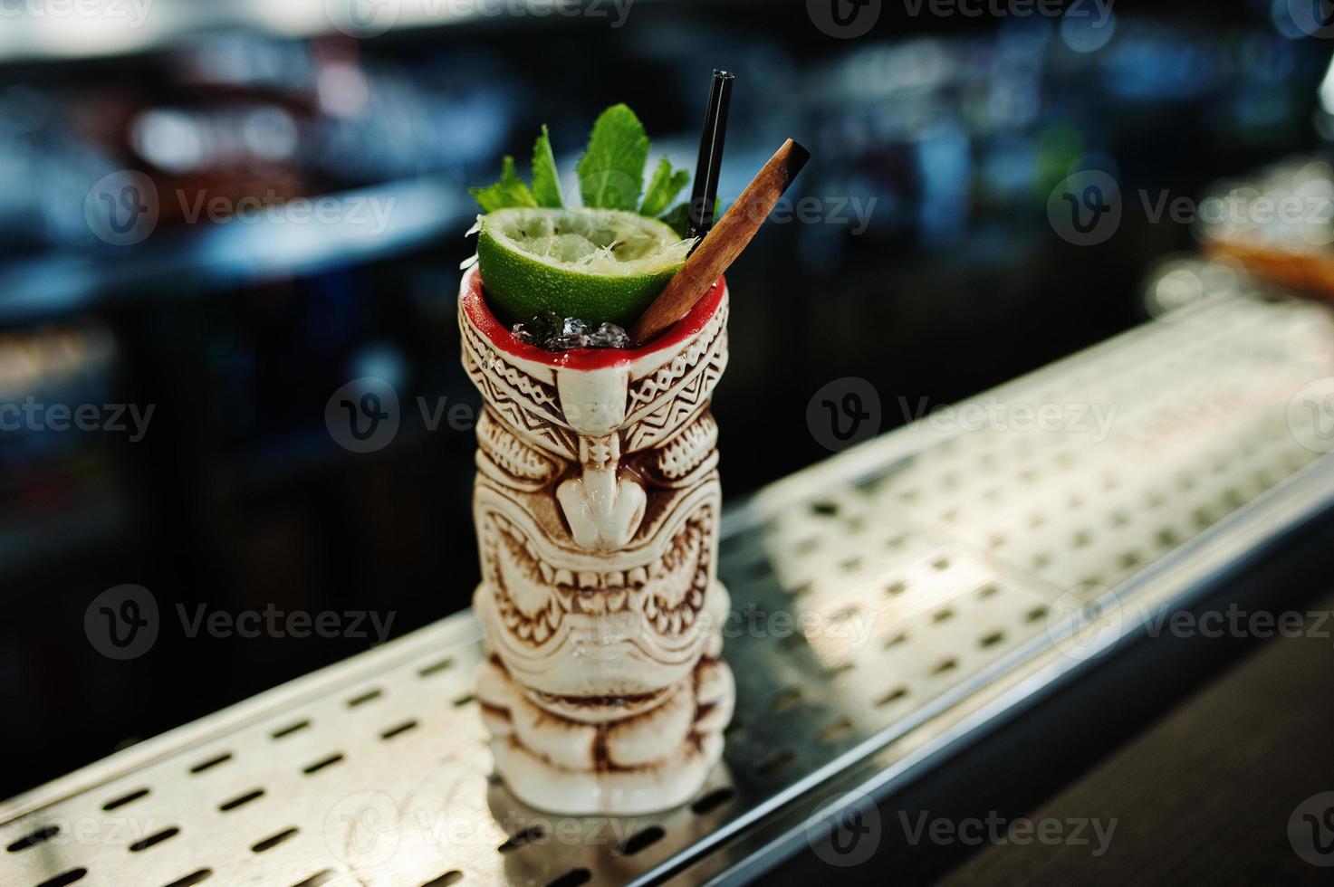 Alcoholic cocktail with mint and lime in originally voodoo earthen glass on bar table. photo