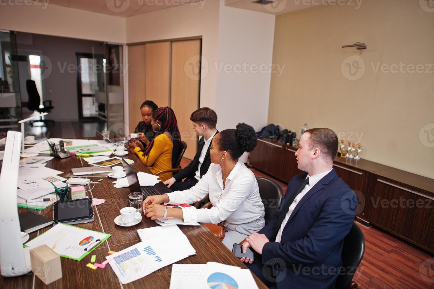 Multiracial business team addressing meeting around boardroom table. photo