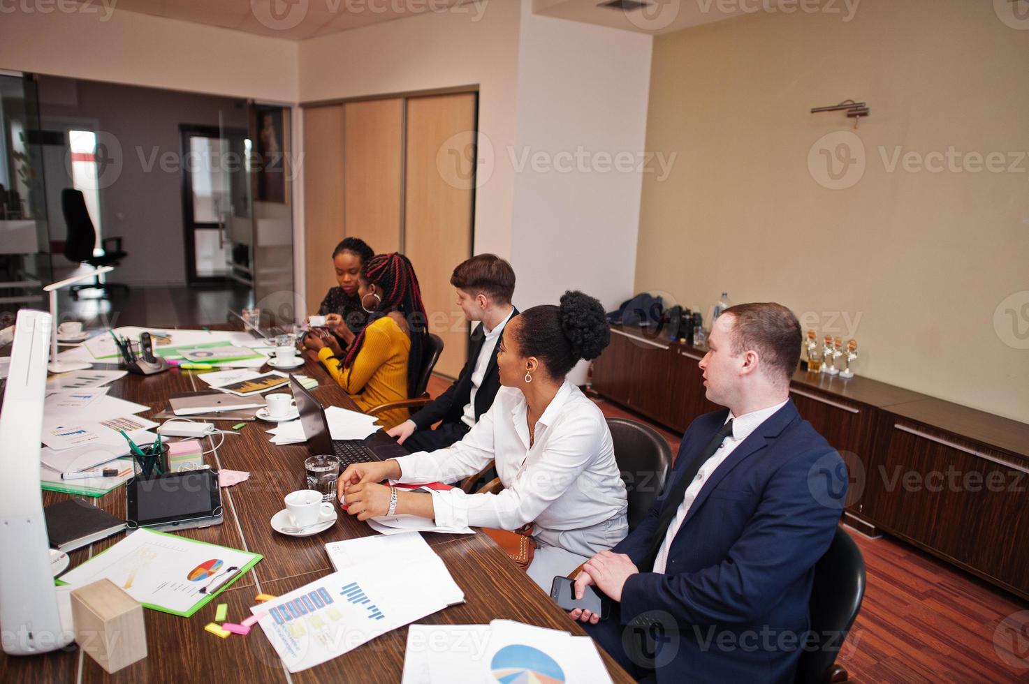 equipo de negocios multirracial que aborda la reunión alrededor de la mesa de juntas. foto