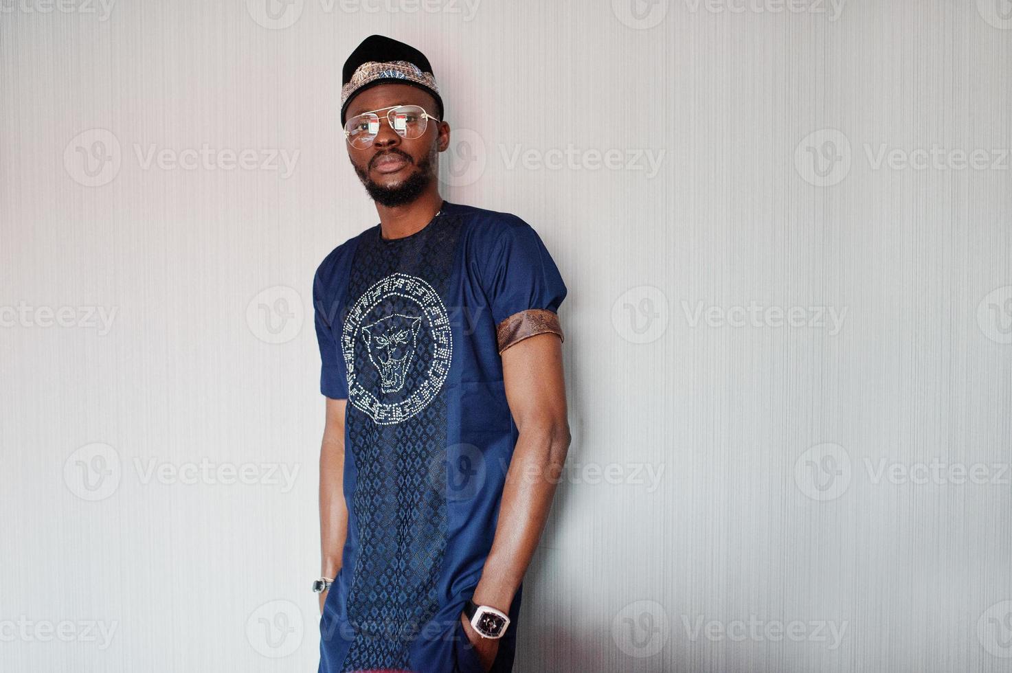 Rich african man in stylish traditional clothes and hat in glasses posed at studio against white background. photo