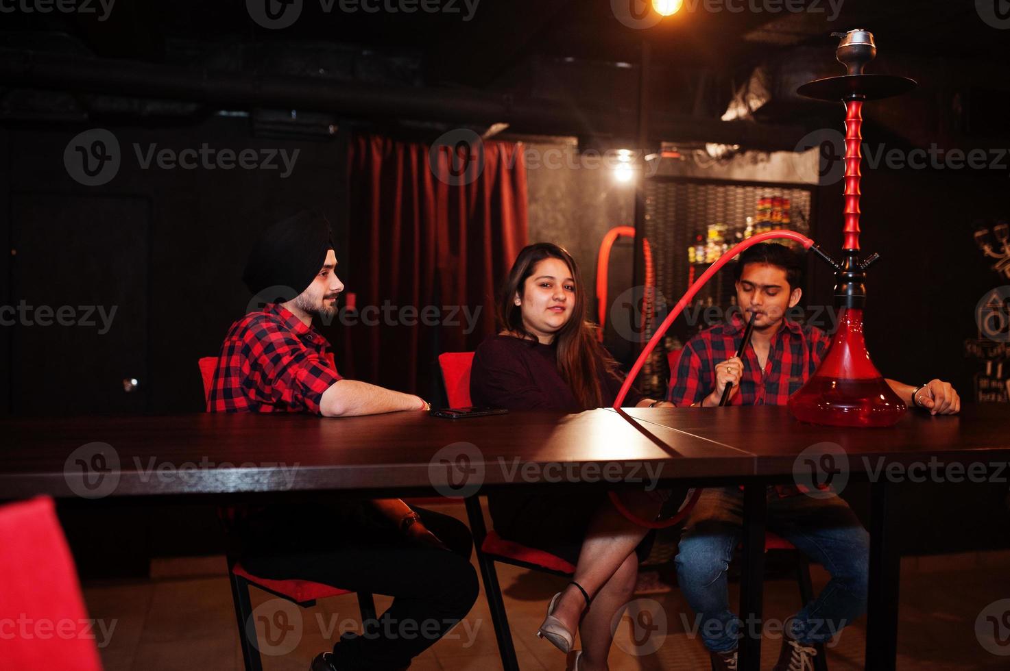 Group of indian friends sitting at lounge bar, smoke hookah and having rest. photo