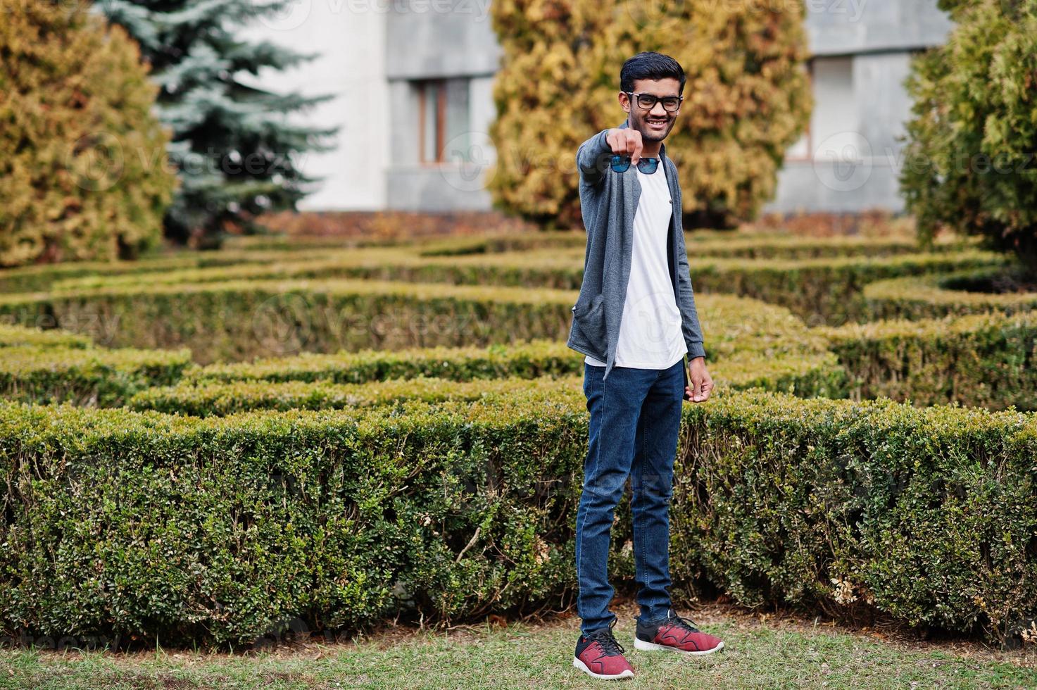 Stylish indian man at sunglasses wear casual posed outdoor and show double glass of glasses. photo