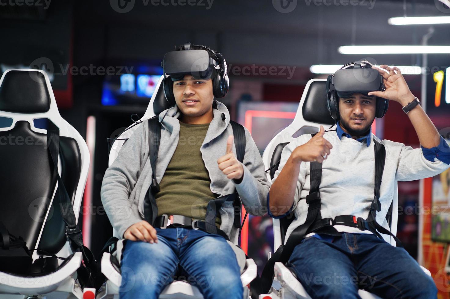 Two young indian people having fun with a new technology of a vr headset at virtual reality simulator. They happy and show thumb up. photo