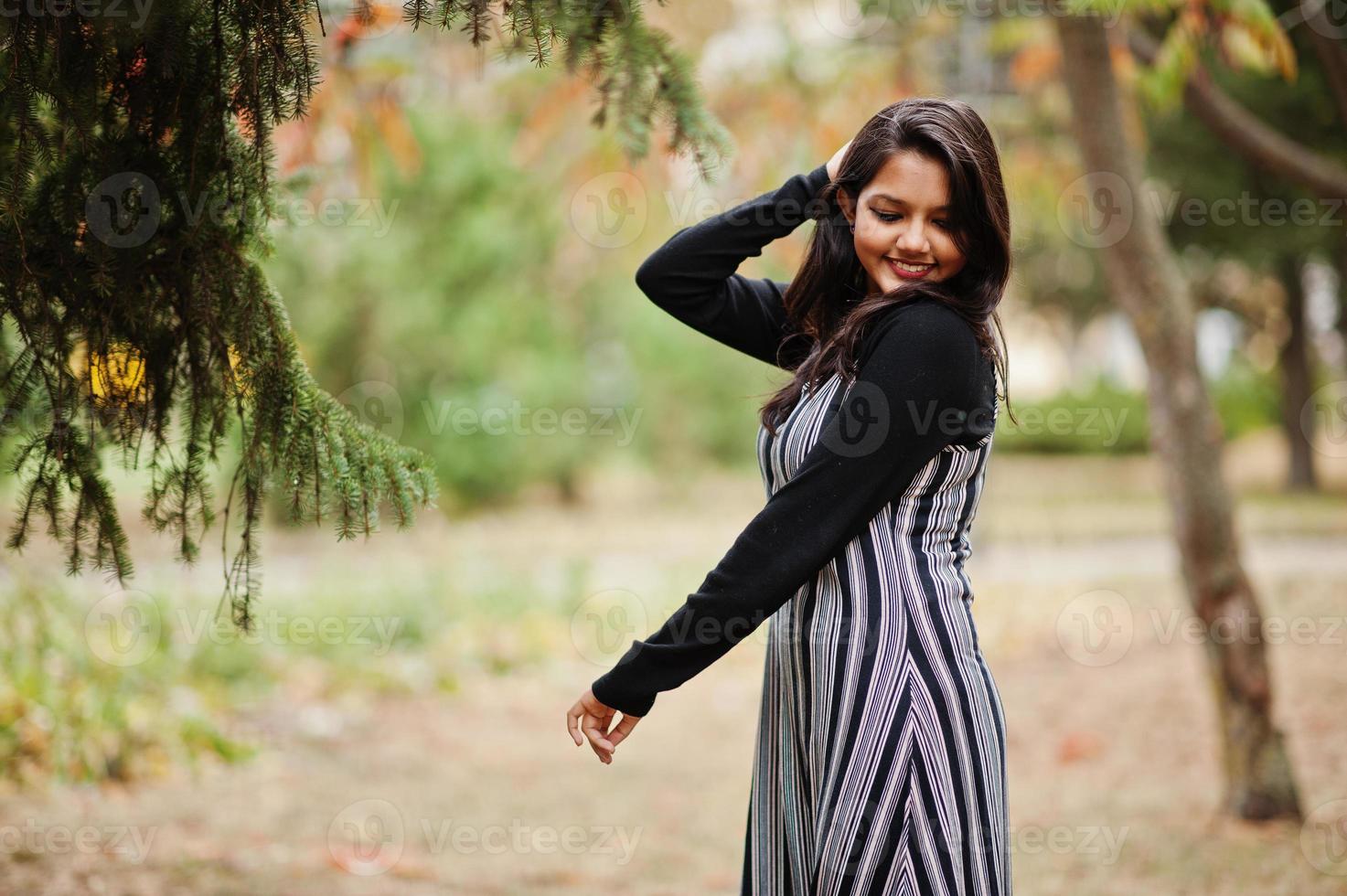 Portrait of young beautiful indian or south asian teenage girl in dress posed at autumn park in Europe. photo