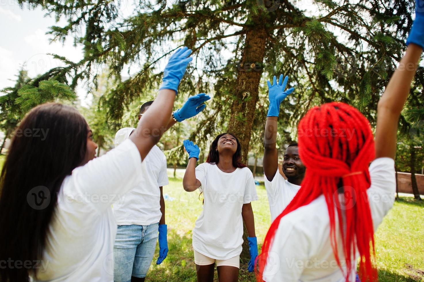 Group of happy african volunteers put hands in hands in park. Africa volunteering, charity, people and ecology concept. photo