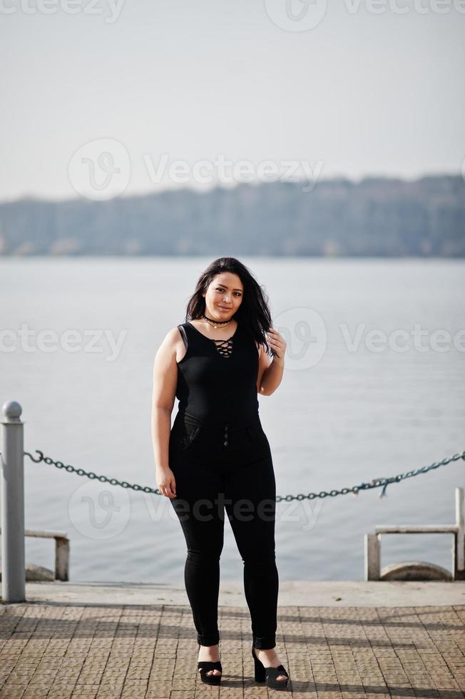 Pretty latino model girl from Ecuador wear on black posed against lake. photo