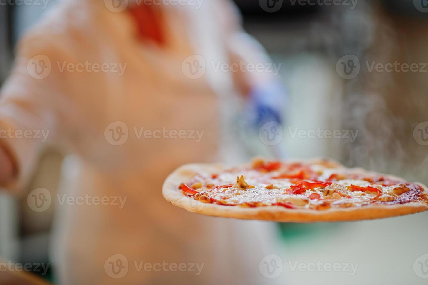 Feale chef preparing pizza in restaurant kitchen. photo