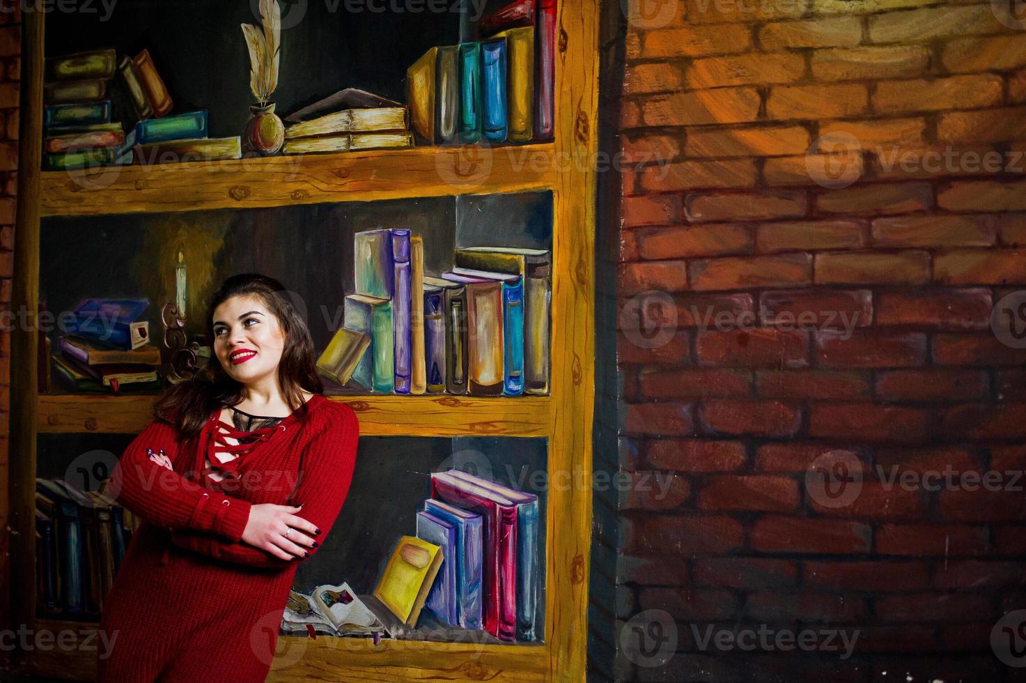 Brunette plus size model against wall like library. photo