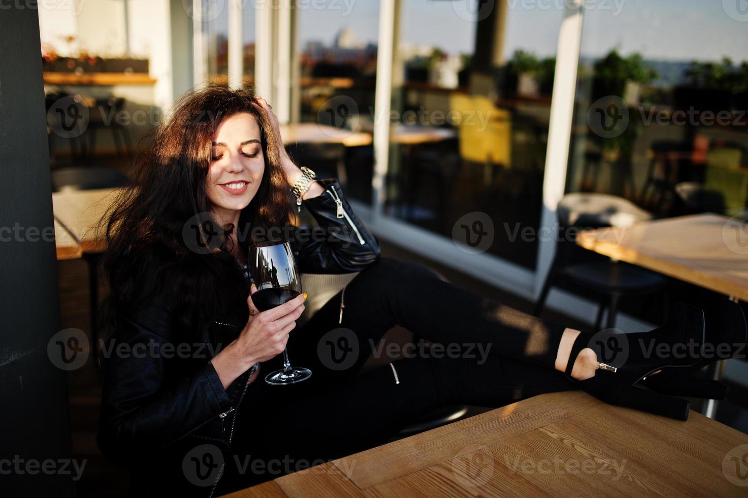 Young curly woman enjoying  her wine in a bar. photo