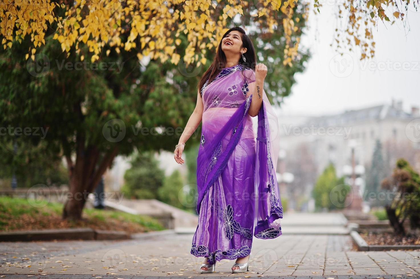 Indian hindu girl at traditional violet saree posed at autumn street. photo