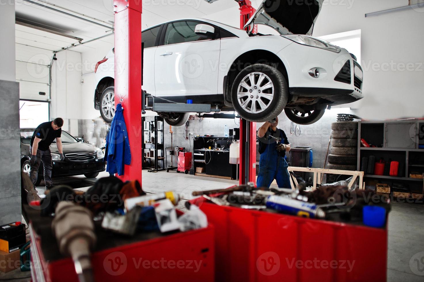 Car repair and maintenance theme. Mechanic in uniform working in auto service. photo