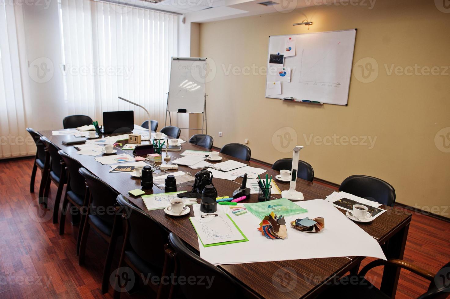 Modern business office interior containing tables and chairs, laptop, camera and office supplies with no employees. photo