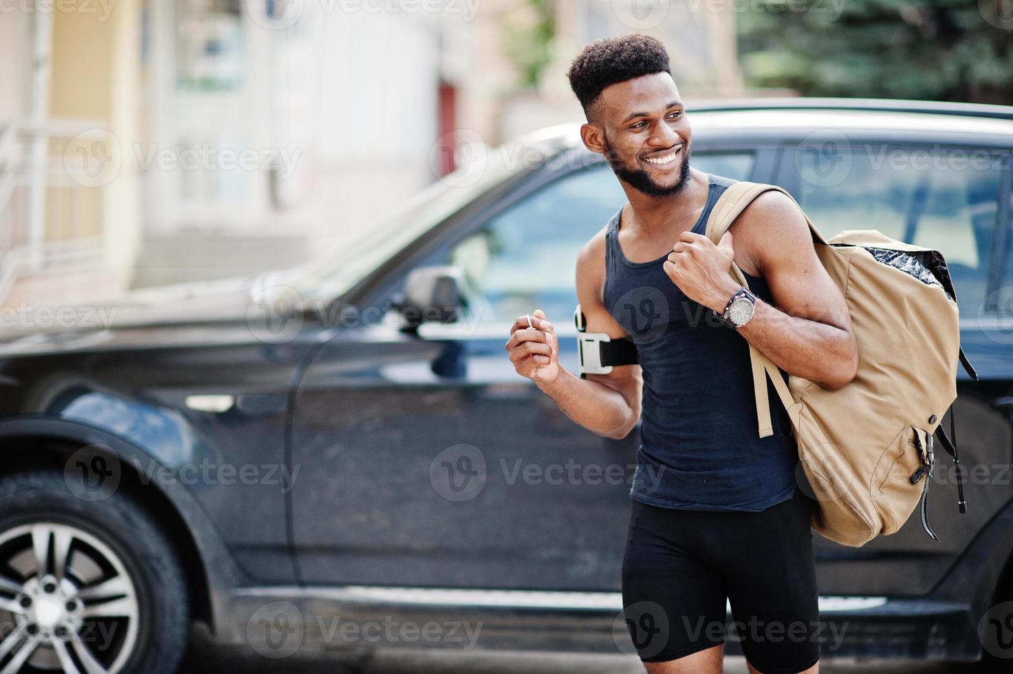 African american male athlete sport man with backpack against his black suv car before training. photo