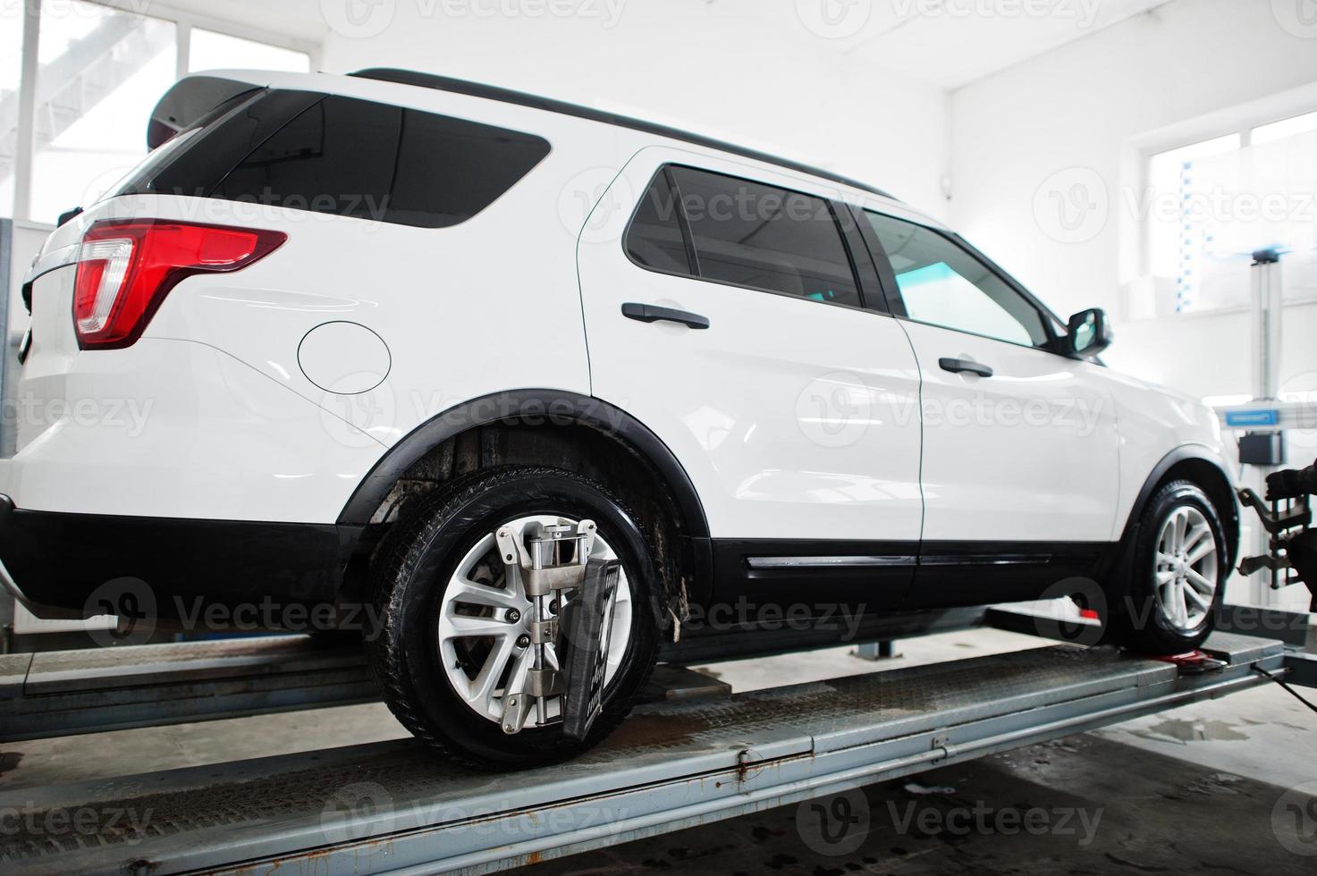 American SUV car on stand for wheels alignment camber check in workshop of service station. photo