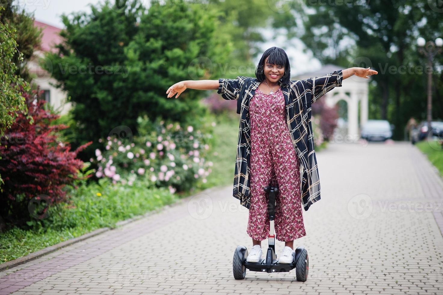 Beautiful african american woman using segway or hoverboard. Black girl on dual wheel self balancing electrical scooter. photo