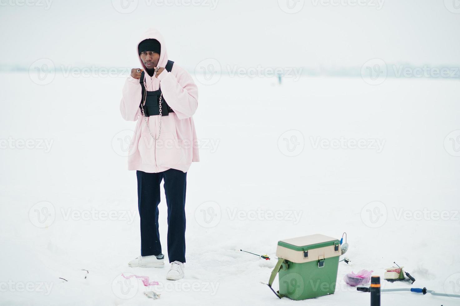 African american fisherman on frozen sea. Winter fishing. photo