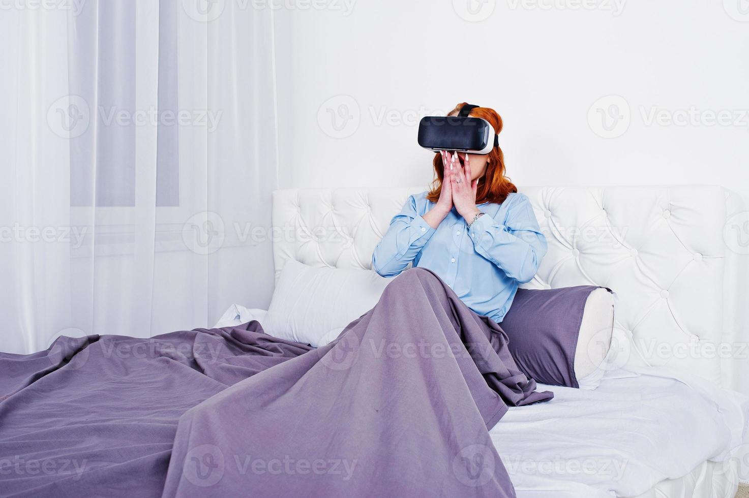 Red haired girl in bed with vr glasses at studio room. photo