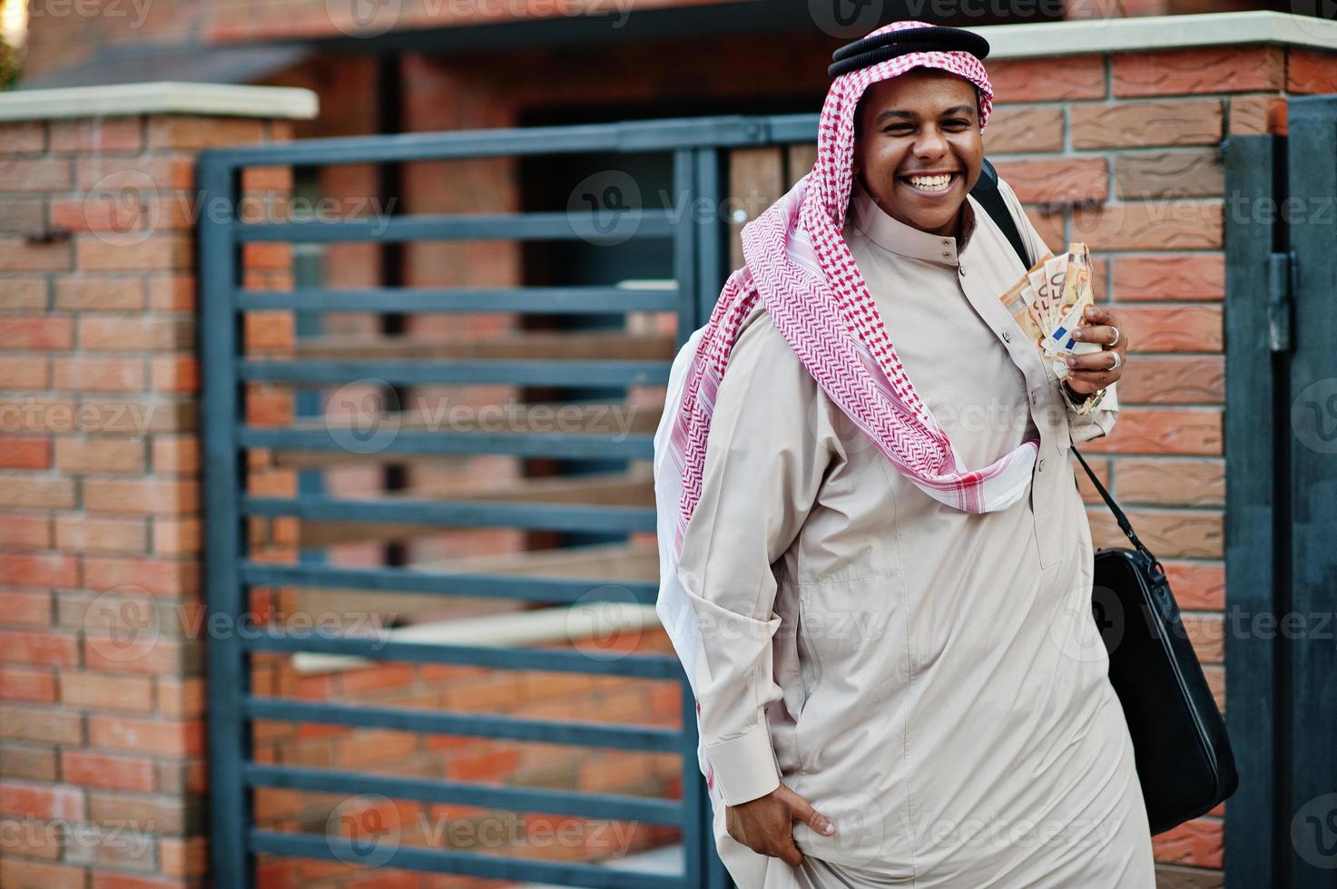 Middle Eastern arab business man posed on street against modern building with black handbag and euro moneys. photo