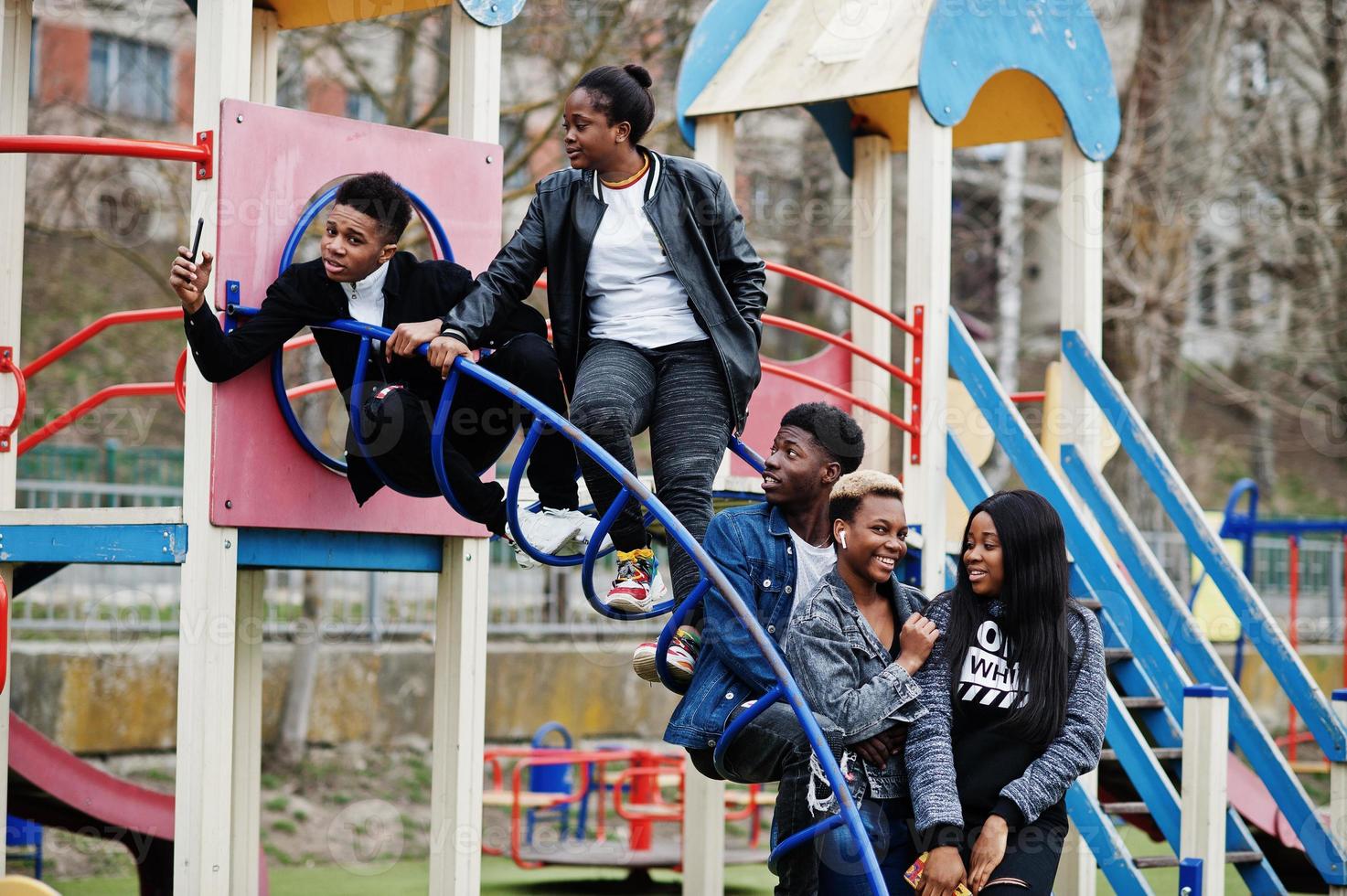 Young millennials african friends on playground, slide and swing. Happy black people having fun together. Generation Z friendship concept. photo