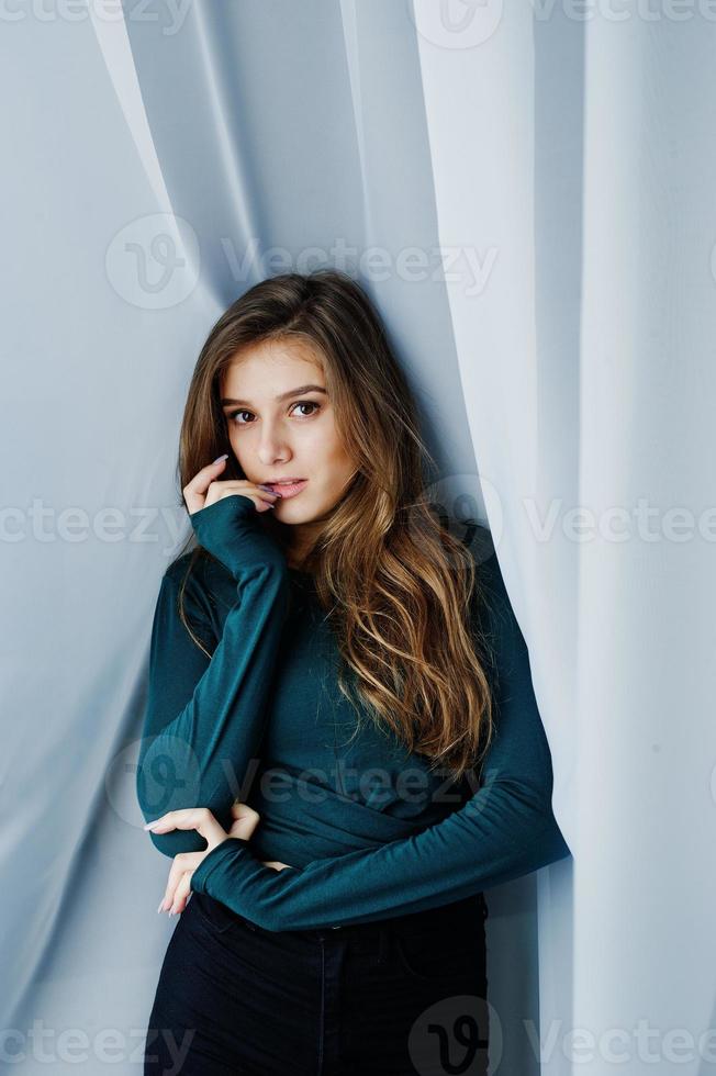 Handsome brunette girl wear on green, posing at curtains. Studio model portrait. photo