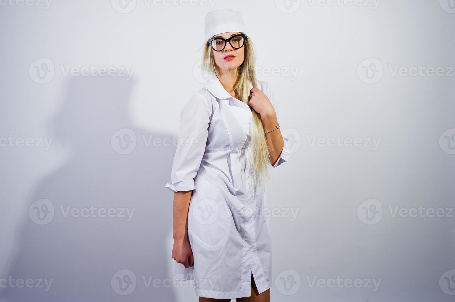 Attractive blonde female doctor or nurse  in lab coat and glasses isolated on white background. photo