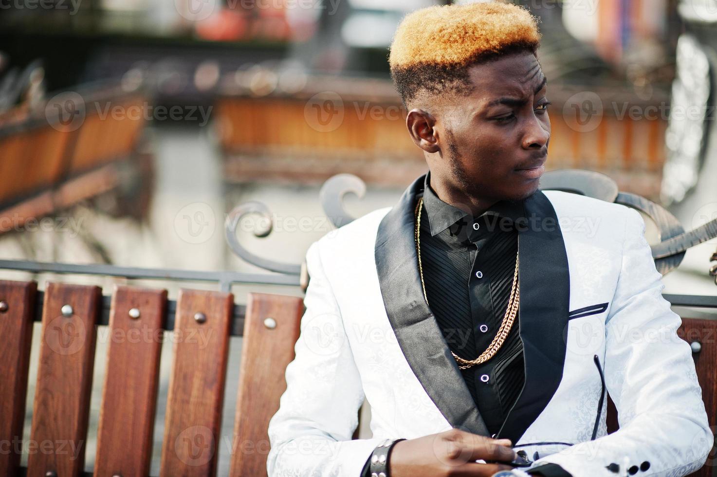 Chic handsome african american man in white suit sitting on bench. photo