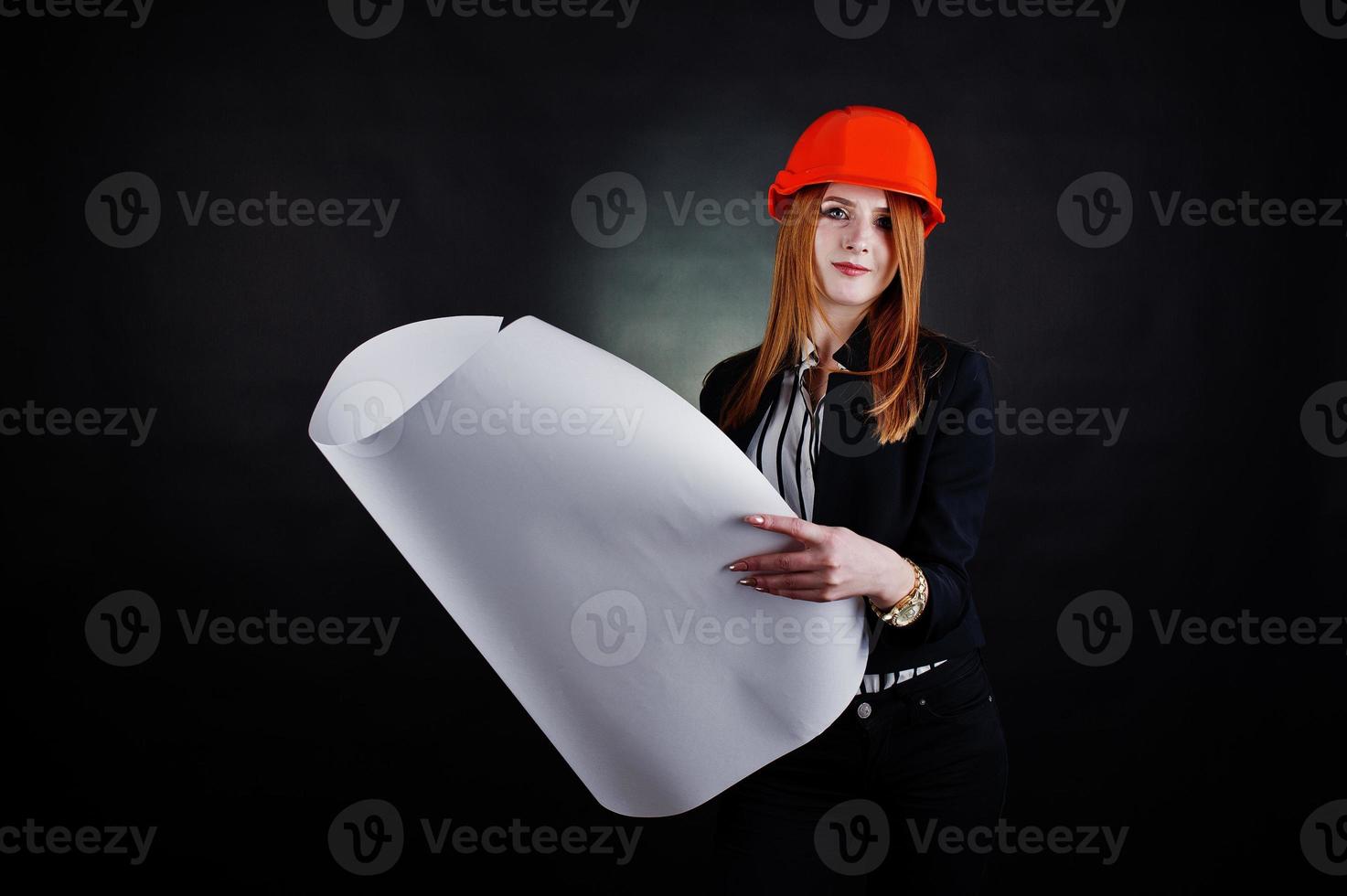 Engineer woman in orange protect helmet with construction paper projekt. photo